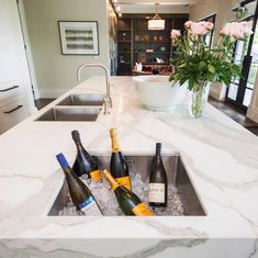 three bottles of champagne are sitting in an ice bucket on the kitchen sink countertop