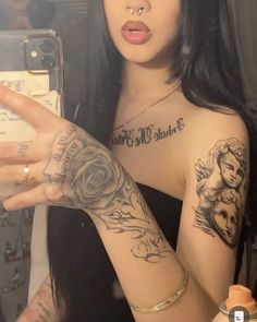 a woman with long black hair and tattoos on her arm taking a selfie in front of a mirror