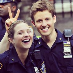 two police officers are smiling and giving the peace sign