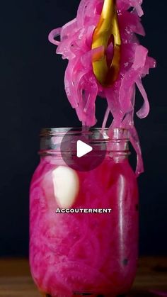 a glass jar filled with pink liquid and a yellow object sticking out of it