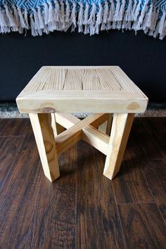 a wooden bench sitting on top of a hard wood floor next to a blue blanket