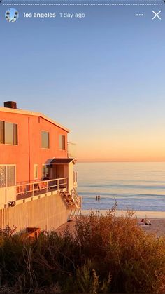 an orange building sitting on top of a sandy beach next to the ocean at sunset