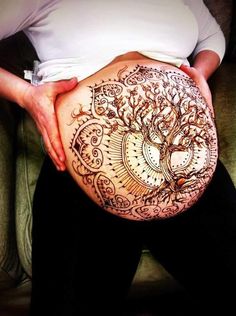 a pregnant woman's belly with henna tattoos on her stomach and the tree of life painted on it