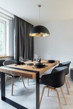 a dining room table with black chairs and a light hanging over it