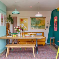 a dining room table with two chairs and some pictures on the wall behind it,