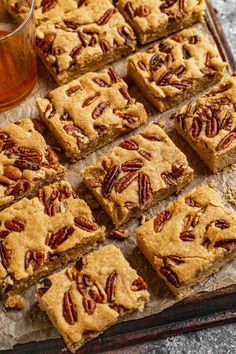 several pieces of pecan bars sitting on top of a tray next to a glass of tea