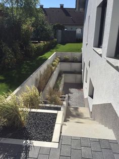 an empty courtyard with some plants in the center and grass on the other side, next to a building