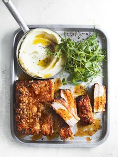 the meal is prepared and ready to be eaten on the tray, including chicken, mashed potatoes, and greens