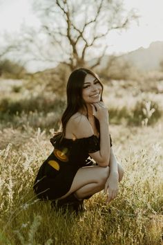 a woman is sitting in the grass and posing for a photo with her hand on her chin