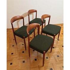 four wooden chairs with green upholstered seats on a hard wood flooring area