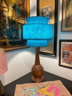 a blue lamp sitting on top of a wooden table next to pictures and other items