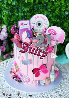 a pink birthday cake with the word juicy on it and lots of stuff around it