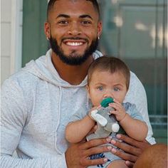 a man holding a baby and smiling at the camera