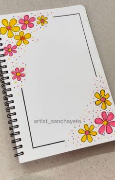 a spiral notebook with flowers painted on the front and bottom cover, sitting on a table