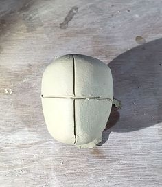 a white piece of pottery sitting on top of a wooden table next to a knife