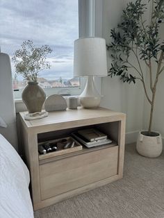 a white lamp sitting on top of a wooden table next to a window sill