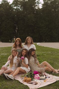 a group of women sitting on top of a grass covered field next to each other