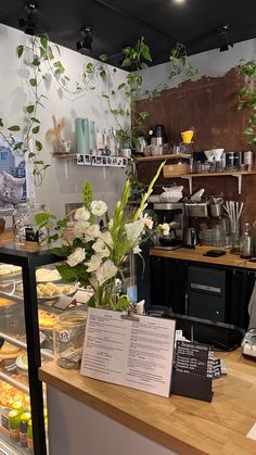 a counter with food and flowers on it in a room that is being used as a coffee shop