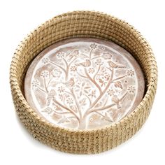 a wicker bowl with an intricate tree design on the bottom and sides, sitting in front of a white background