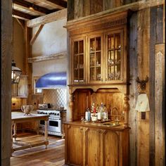 an old fashioned kitchen with wood paneling and wooden cabinets in the middle of it