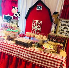 a table topped with lots of desserts next to a red barn and white curtains