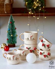 a white table topped with cups filled with christmas decorations next to a small christmas tree