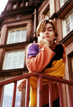 a young man standing on top of a balcony next to a tall building