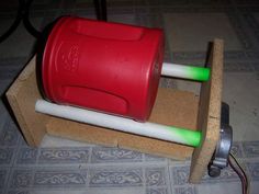 a red and white plastic cup sitting on top of a wooden stand next to a green tube