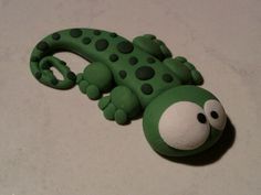 a green toy with black dots on it's face and eyes sitting on a white surface