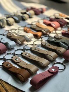 leather keychains are lined up on a table with metal rings in different colors