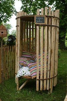 a bed made out of wooden sticks in the grass with a chalkboard attached to it