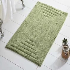 a bathroom rug on the floor next to a potted plant