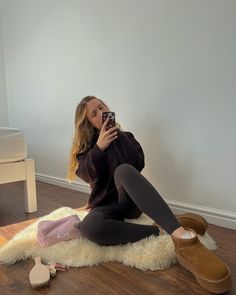 a woman sitting on the floor taking a selfie