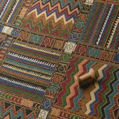 a close up of a colorful rug on the ground with a wooden object next to it