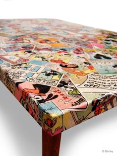 a wooden table topped with lots of comic themed designs on it's top and bottom