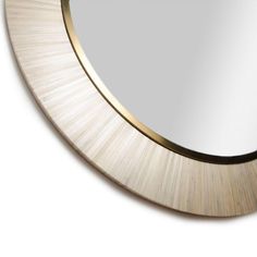 an oval mirror with gold trim around the edges