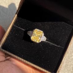 a yellow diamond ring in a black box