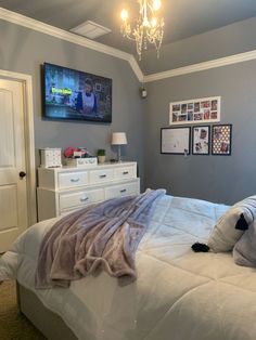 a bedroom with a bed, dresser and television on the wall in it's corner