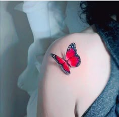 a woman's shoulder with a red butterfly tattoo on the left side of her arm