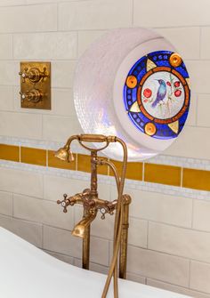 an old fashioned bathtub with a stained glass window on the side and gold faucet