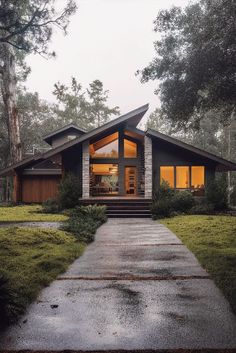 a house that is in the middle of some grass with trees and bushes around it