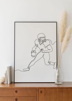 a drawing of a football player on a wall next to a vase with dry grass in it