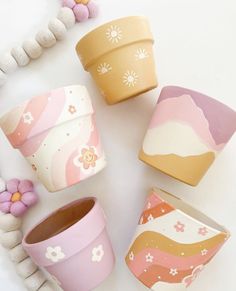 four flower pots sitting next to each other on top of a white table with beads