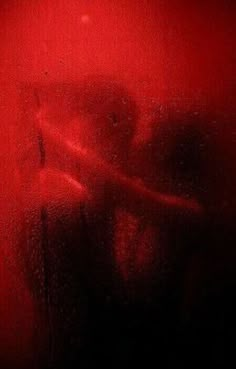 a blurry image of a person standing in front of a red wall with the light coming through it