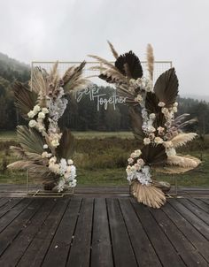 a wooden table topped with lots of flowers and feathers next to a sign that says happily together