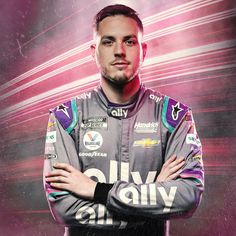 a man with his arms crossed standing in front of a purple and black background wearing a racing suit