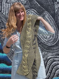 a woman standing in front of a wall with a scarf on it's back