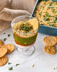 a glass filled with food next to crackers