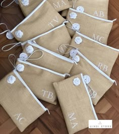 six burlap bags with white monogrammed buttons are on the floor next to each other