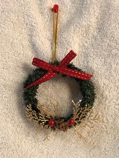 a christmas wreath hanging on a towel with a red bow and pineconis in the middle